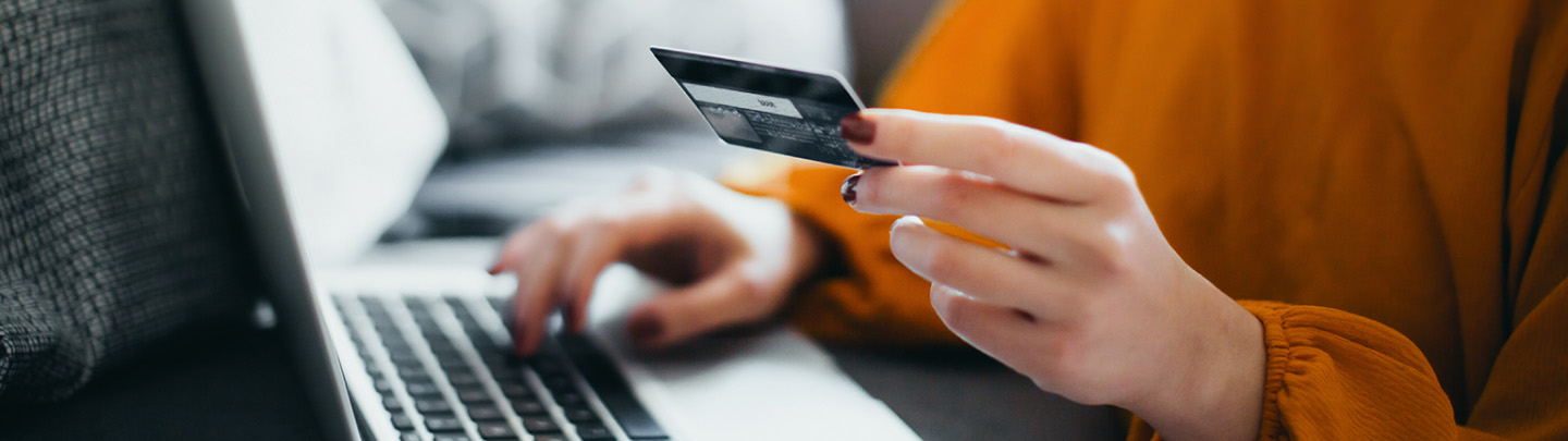 Banner con la imagen de una persona utilizando una notebook mientras sostiene una tarjeta de crédito, representando el pago digital.